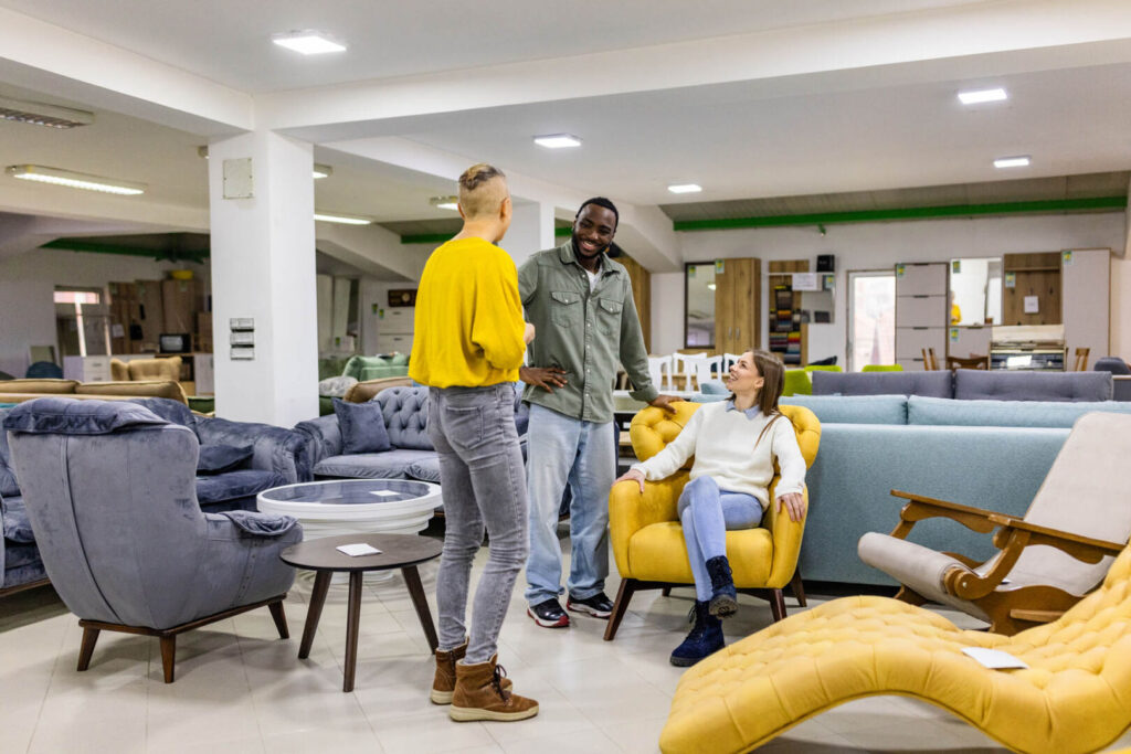A customer shares a laugh amidst an array of stylish furniture in a modern showroom, capturing a moment of joy and relaxed interaction during a shopping experience.