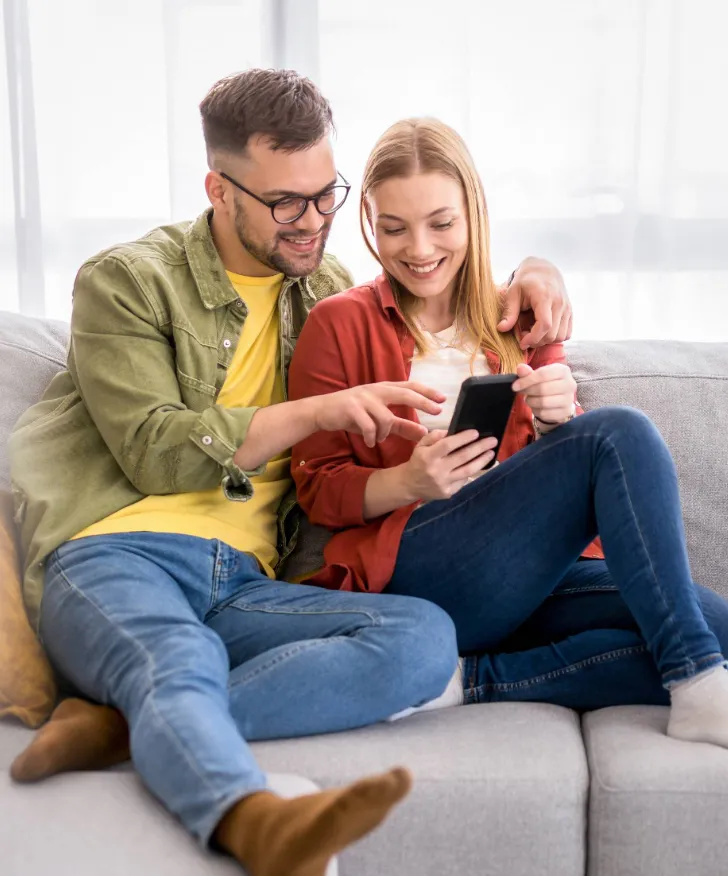 Couple shopping online together on a phone at home