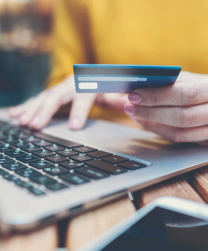Customer holding a bank card while paying on a laptop