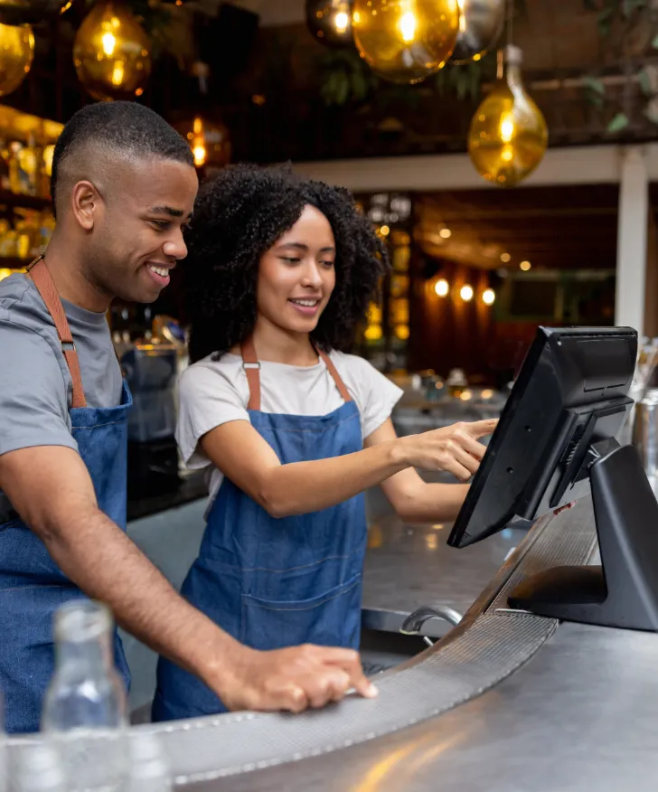Two cafe staff working at the counter till
