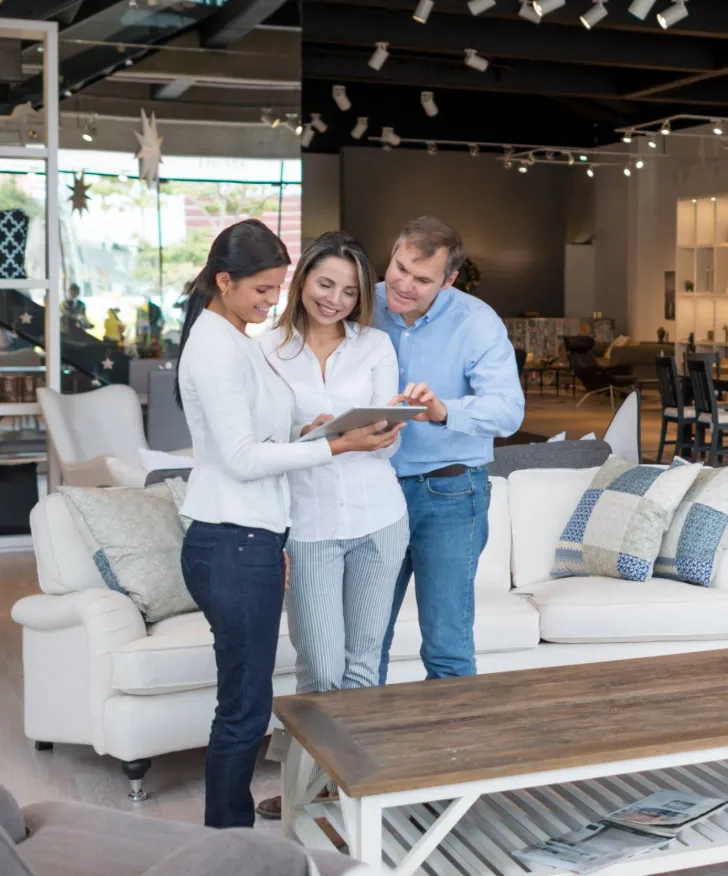 Couple browsing sofas with a sales assistant in a furniture showroom