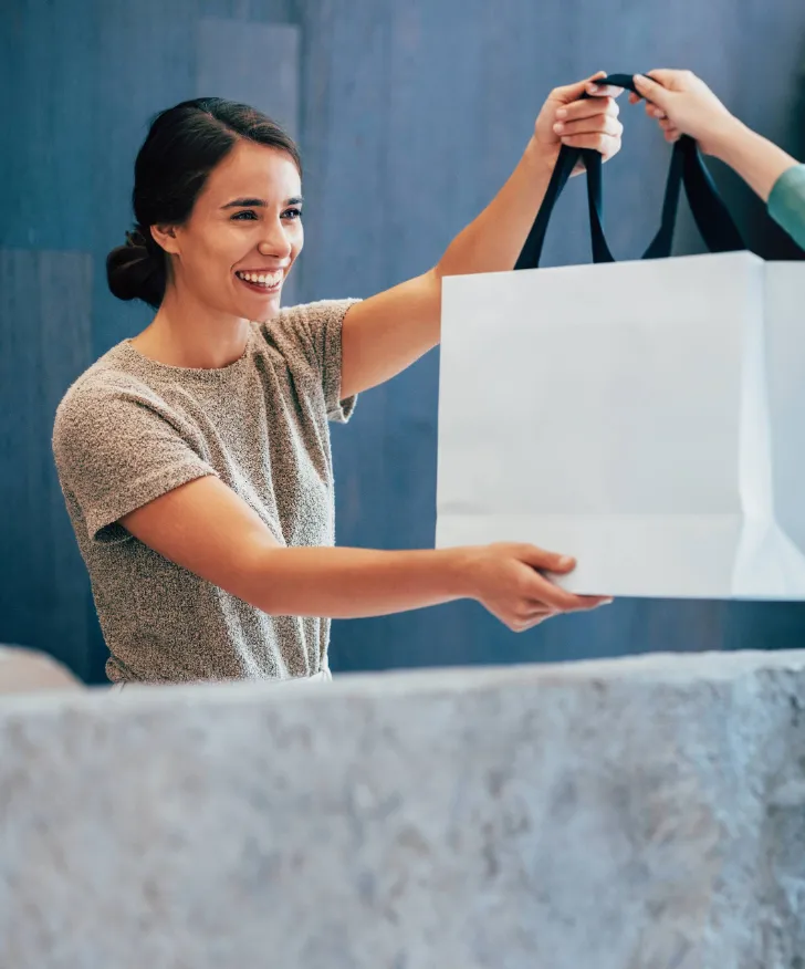 Assistant packing a purchase into a shopping bag at the counter
